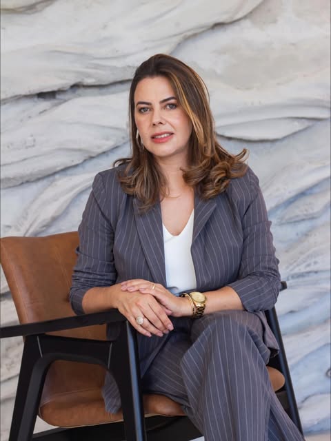 Patricia Mesquita sentada, de terno risca de giz, em seu escritório